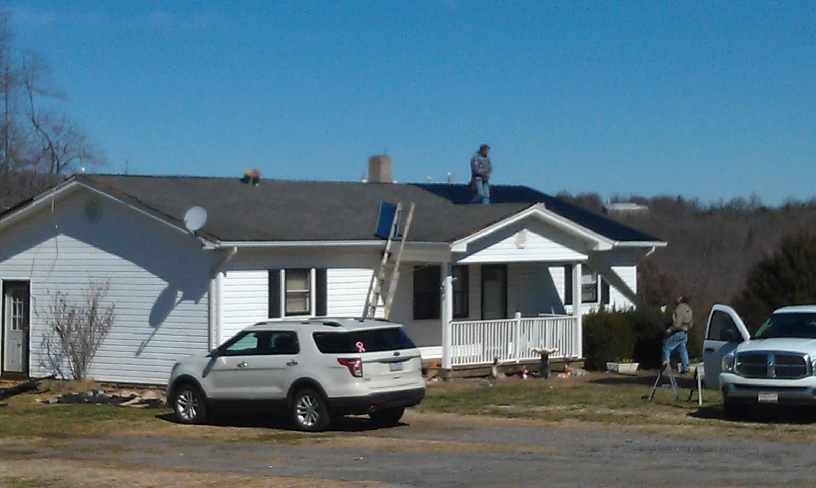 Roofers stripping shingles from a white ranch house roof in Rock Island